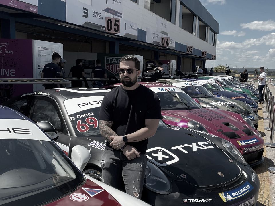 Caiube sentado sobre um carro de corrida da TXC no autódromo