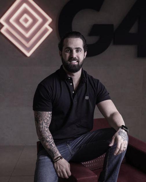 Caiube Nogueira sorrindo, sentado numa poltrona